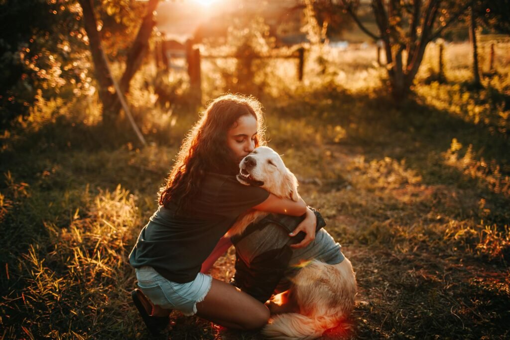 Mulher abraçando seu Golden Retriever durante pôr do sol em campo gramado