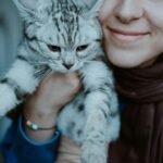 Mulher feliz segurando seu gato British Shorthair dentro de casa