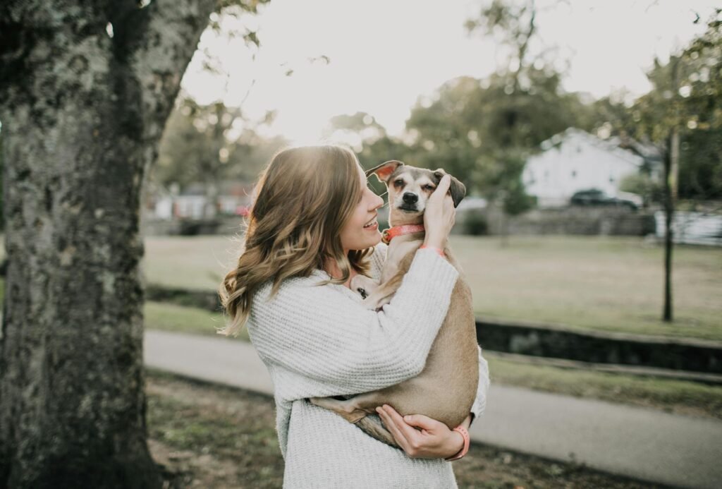 Mulher feliz abraçando seu cachorro ao ar livre em parque ensolarado, demonstrando afeto e união